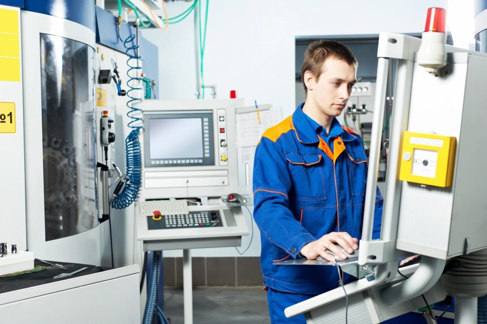 A man in blue and orange work clothes working on a computer.