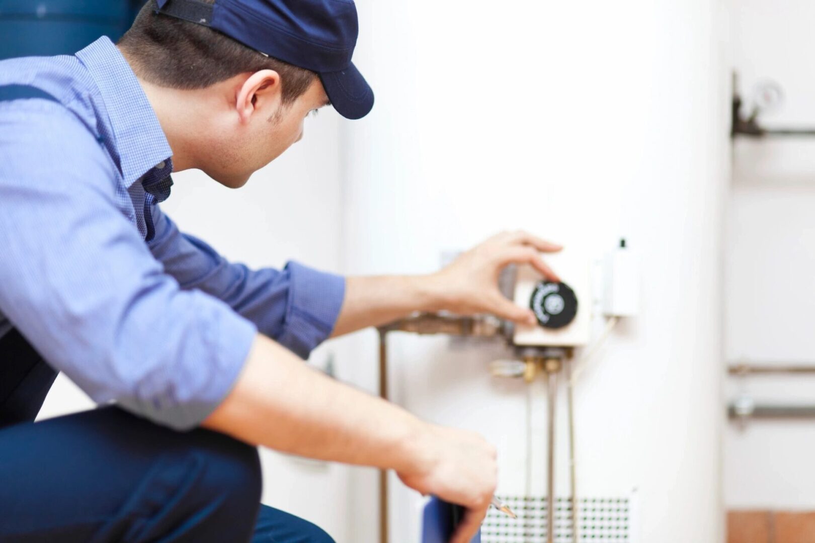 A man is fixing the water heater on the wall.