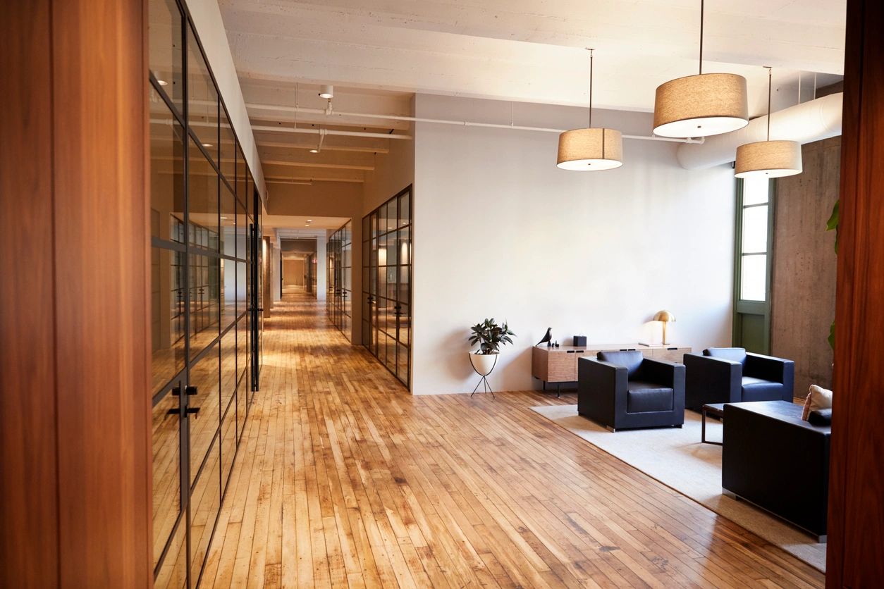 A long hallway with wooden floors and glass walls.